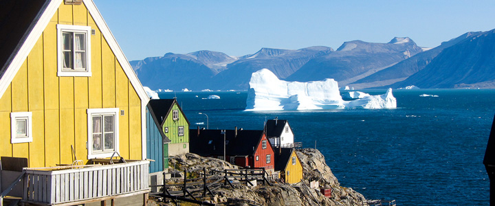 Uummannaq im Norden Westgrönlands liegt mit bunten Holzhäusern vor einer eindrucksvollen Fjordlandschaft. Eisberge prägen die arktische Kulisse.